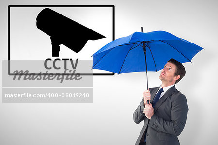 Businessman sheltering under blue umbrella against cctv