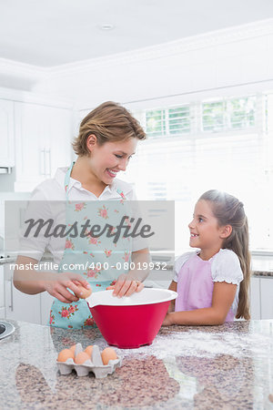 Mother and daughter baking together at home in kitchen