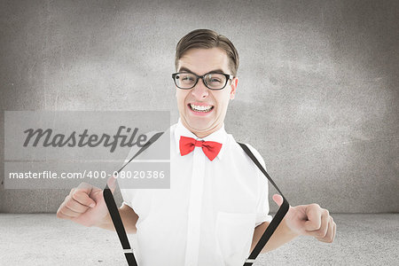 Geeky hipster pulling his suspenders against grey room