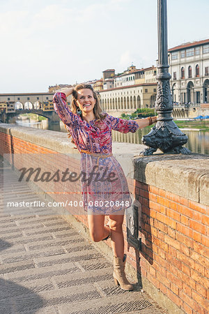 Happy young woman having fun time walking on embankment near ponte vecchio in florence, italy