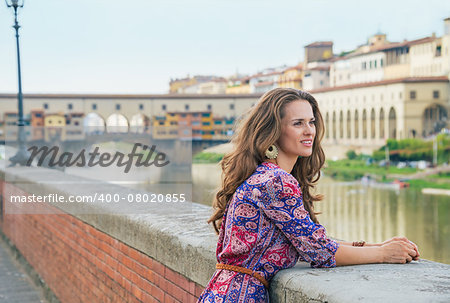 Thoughtful young woman on embankment near ponte vecchio in florence, italy