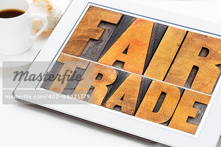 fair trade word abstract typography -  text in letterpress wood type on a digital tablet with a cup of coffee