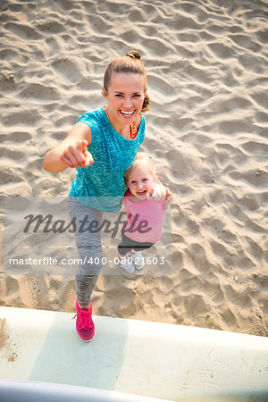 Portrait of healthy mother and baby girl pointing while on beach