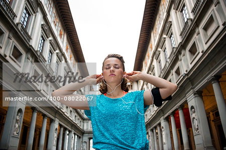 Fitness woman wearing earphones near uffizi gallery in florence, italy