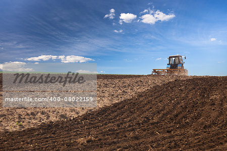 Agricultural Lanscape - Tractor working on the field - spring sunny day