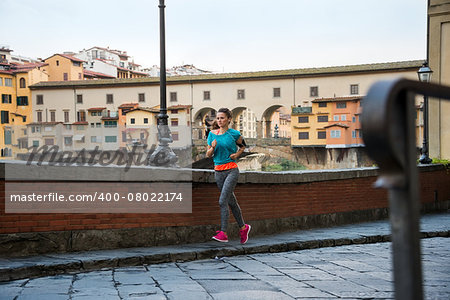 Fitness woman jogging near ponte vecchio in florence, italy