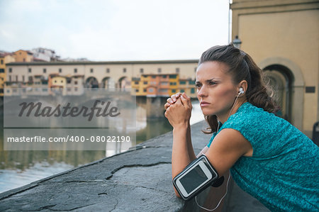 Thoughtful fitness woman standing in front of ponte vecchio in florence, italy