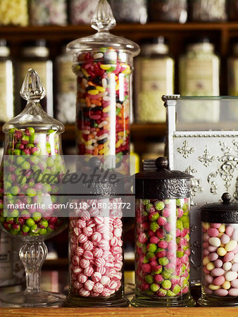 Traditional sweets displayed in tall glass jars on the shelves of a sweet shop.
