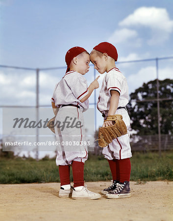 1960s TWO BOYS WEARING LITTLE LEAGUE BASEBALL UNIFORMS HEAD TO HEAD IN ANGRY ARGUMENT