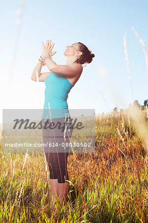 Mature woman practising yoga on field