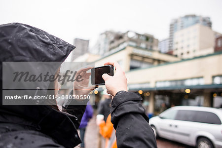 Female tourist photographing on smartphone at Pike Place market, Seattle, Washington State, USA