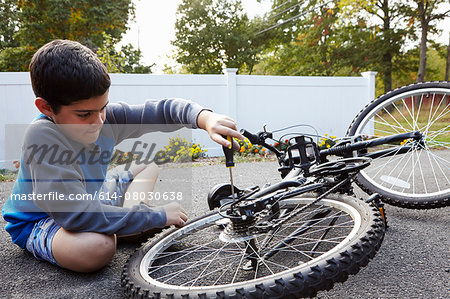 Determined boy repairing bicycle on driveway