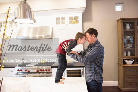 Father face to face and holding son on kitchen counter