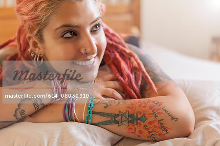 Portrait of young woman with pink dreadlocks lying on bed