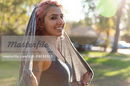 Portrait of young woman with pink dreadlocks and shawl in park