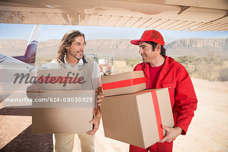 Delivery men carrying parcels off airplane