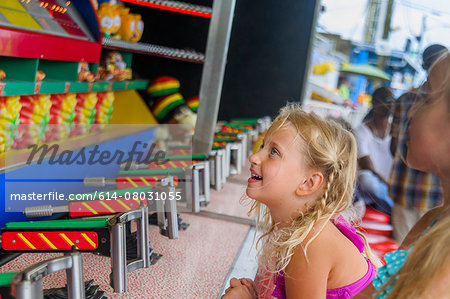 Two sisters looking up in front of  fairground stall