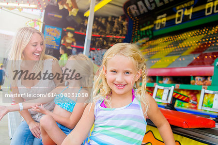 Portrait of girl with sister and mother in front of fairground stall