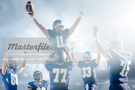 Teenage and young male American football team celebrating on pitch Teenage and young male American football team celebrating on pitch