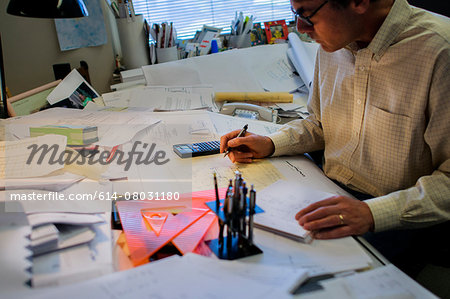 Architect sitting at desk, putting together plans