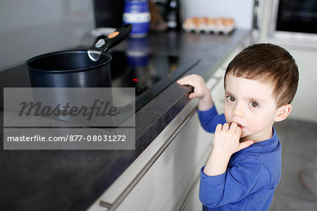 A little boy in front of a pot of boiling water