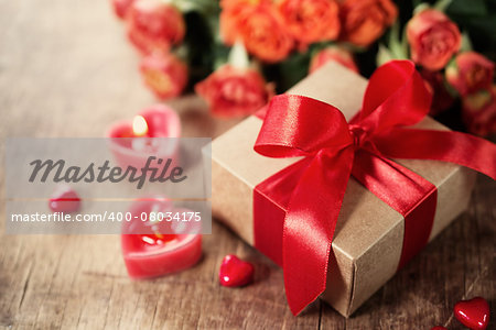 Gift with red bow and heart-shaped candles on the wooden background, Valentines