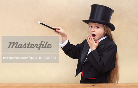 Surprised magician girl with magic wand - copy space on golden background
