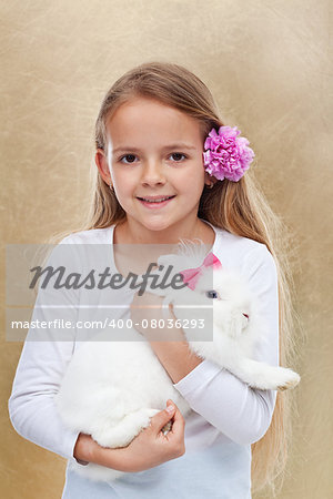 Cute little girl holding her white rabbit - portrait on golden background