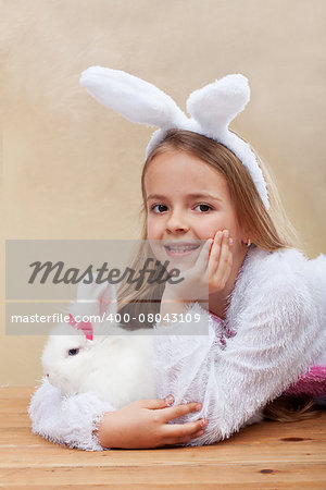 Happy girl in bunny costume holding her white rabbit - laying on wooden floor