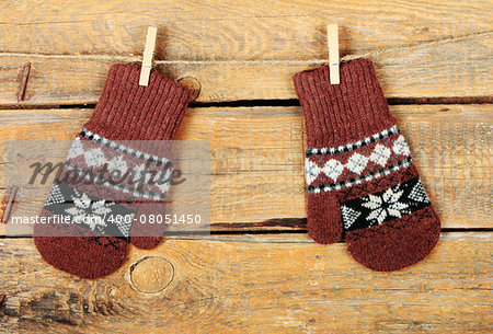 Pair of brown mitten with ethnic ornament on old wooden background