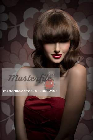 Pretty, mysterious, gorgeous woman with smooth brown hair with straight fringe wearing red, satin top, big old necklace and red lipstick, her eyes are in shadow.