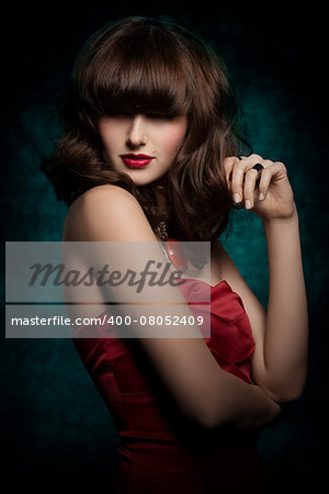 Pretty, mysterious, gorgeous woman with smooth brown hair with straight fringe wearing red, satin top, big old necklace and red lipstick, her eyes are in shadow.