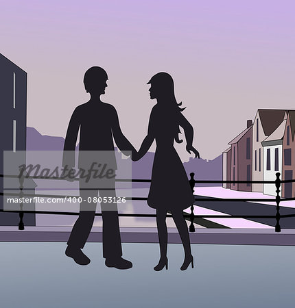 The silhouettes of a couple standing on a bridge in a town.