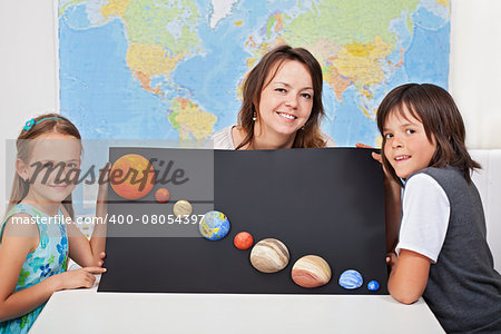 Kids with their science teacher showing their home project - planets of the solar system