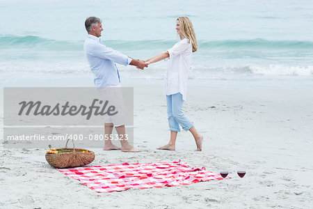 Happy couple standing by the sea and holding hands at the beach