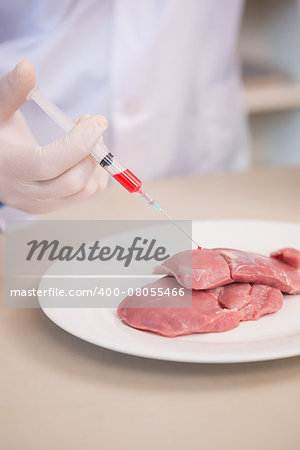 Scientist doing injection to pieces of meat in the laboratory