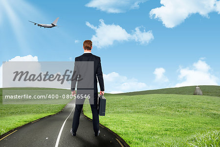 Rear view businessman standing with his briefcase against road leading out to the horizon