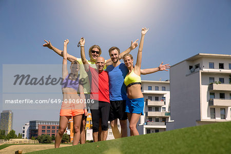 Group of people in sportswear, smiling with arms raised