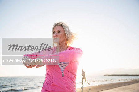 Senior woman stretching by beach