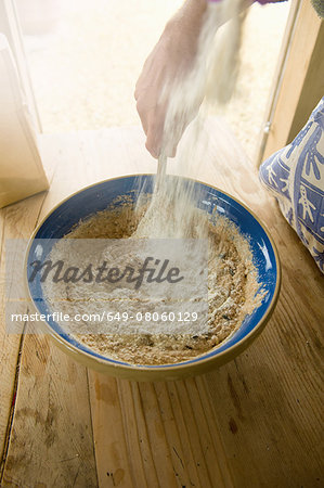 Mature man making organic bread, focus on hands and bread