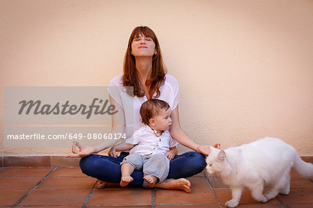 Portrait of mid adult woman practicing yoga with baby daughter on kitchen floor