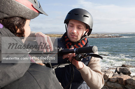 Couple preparing for bicycle ride by seaside, Connemara, Ireland