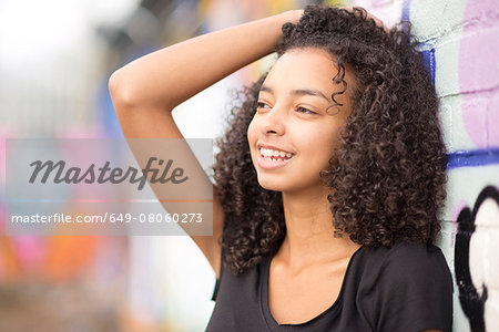 Teenager leaning against wall with graffiti