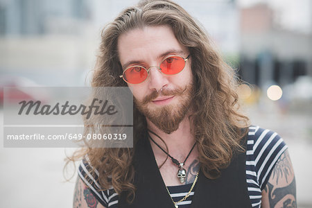 Portrait of young male hippy with orange sunglasses and long hair