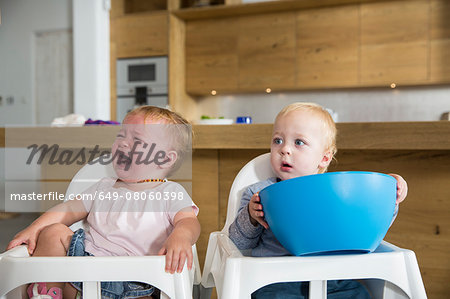 Male and female twin toddlers in high chairs