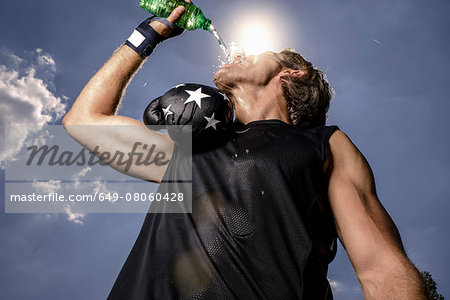 Low angle view of mid adult male boxer drinking bottled water