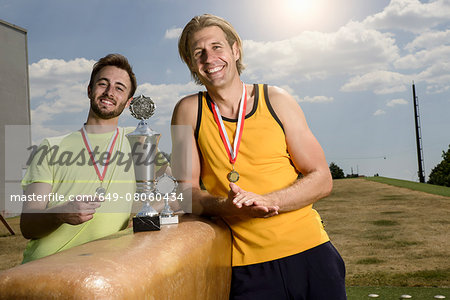Portrait of two male gymnasts with trophies and medals