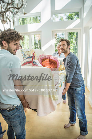 Adult friends moving sofa in living room