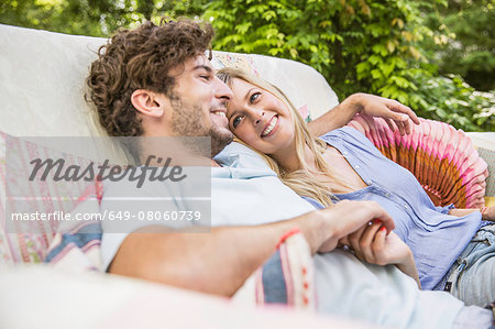 Romantic couple sitting on vintage sofa in garden