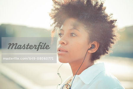 Portrait of pensive young woman listening to earphones